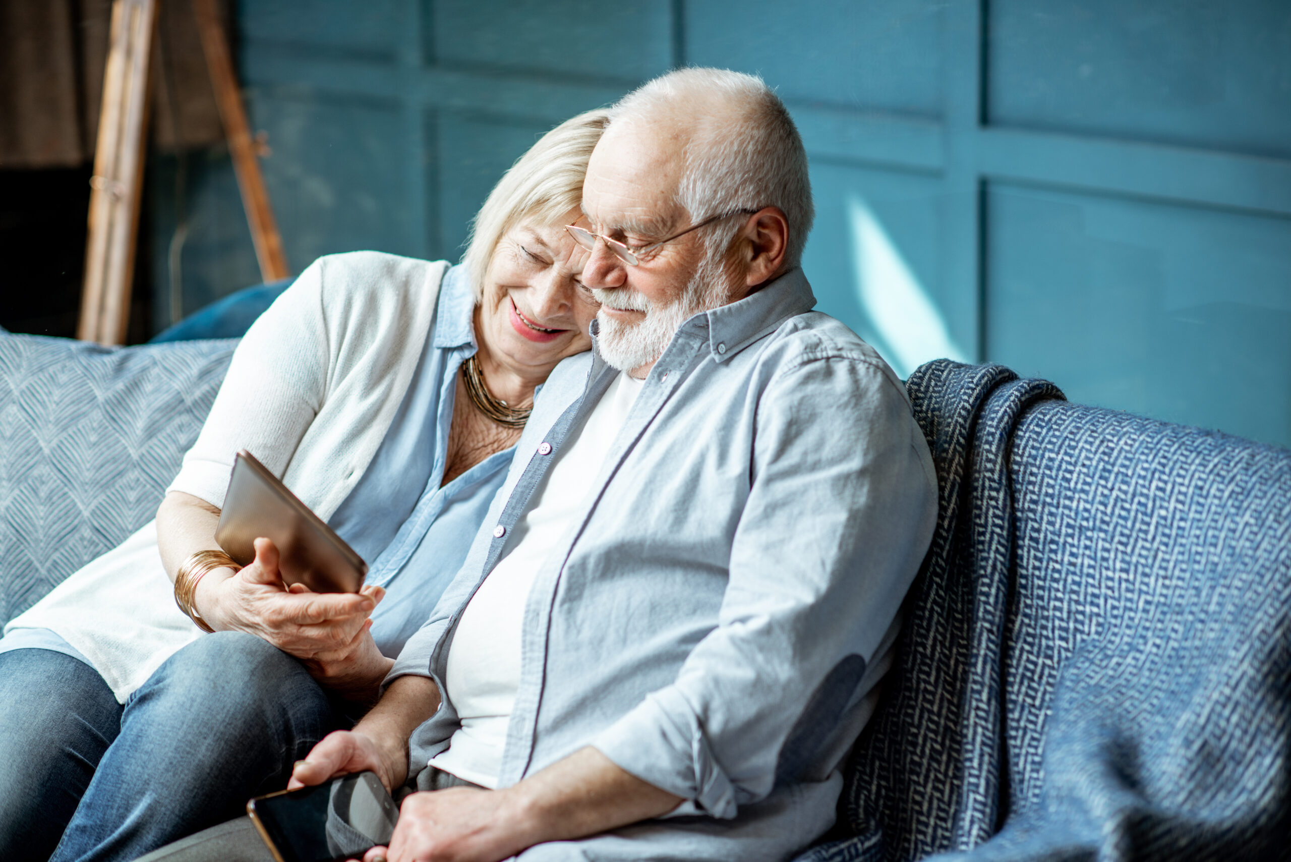 Senior couple with tablet at home Lovely senior couple dressed casually using digital tablet while sitting together on the comfortable couch at home
